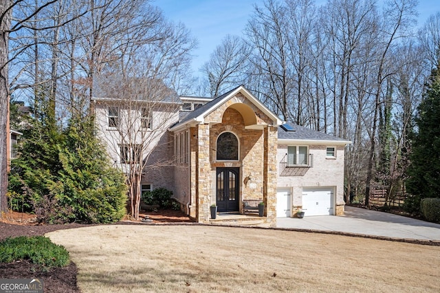 view of front of property with concrete driveway, a garage, brick siding, and stone siding