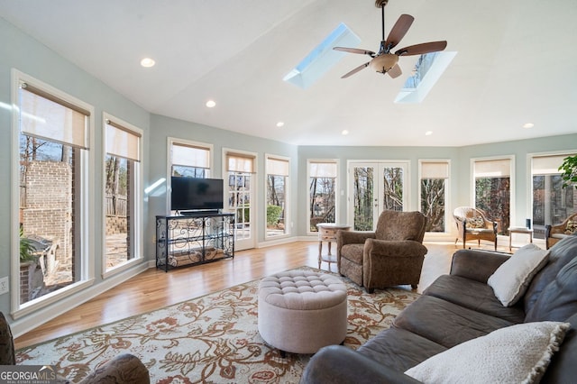 living room featuring vaulted ceiling with skylight, recessed lighting, wood finished floors, and ceiling fan