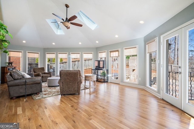 living area featuring ceiling fan, light wood-type flooring, recessed lighting, a skylight, and high vaulted ceiling