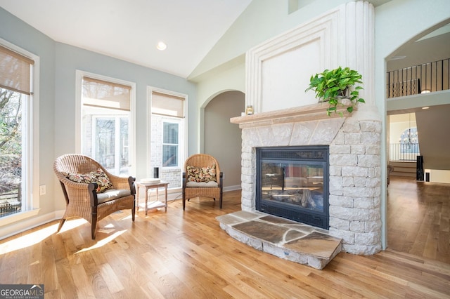 living area with a stone fireplace, recessed lighting, wood finished floors, a notable chandelier, and high vaulted ceiling