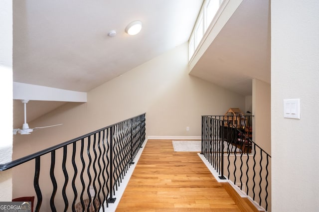 hall featuring an upstairs landing, wood finished floors, and baseboards