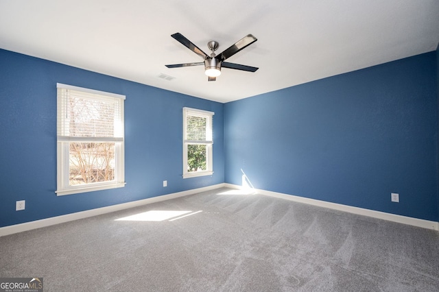 carpeted empty room featuring visible vents, baseboards, and ceiling fan