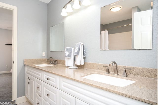 full bath featuring double vanity, a shower with curtain, baseboards, and a sink