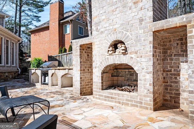 view of patio with grilling area, fence, and an outdoor brick fireplace