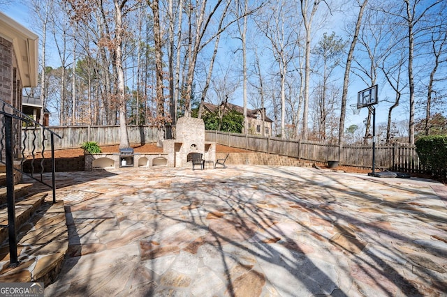 view of patio / terrace featuring a fenced backyard and an outdoor stone fireplace