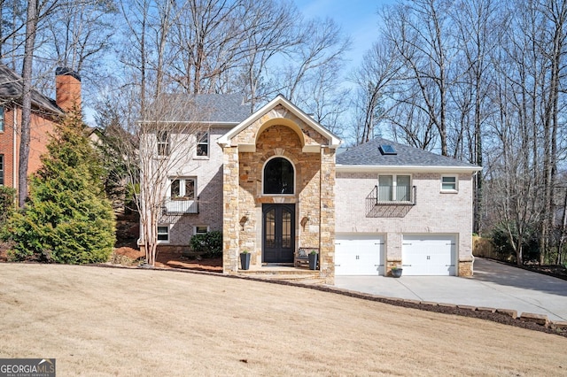 view of front of property with brick siding, concrete driveway, french doors, a balcony, and a garage