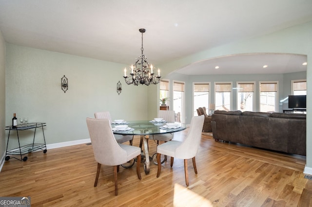 dining space with recessed lighting, light wood-type flooring, arched walkways, and baseboards