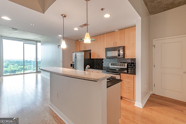 361 17th St Unit 1516, Atlanta, GA 30363 - kitchen with appliances with stainless steel finishes, light brown cabinets, light wood-style floors, backsplash, and a center island with sink