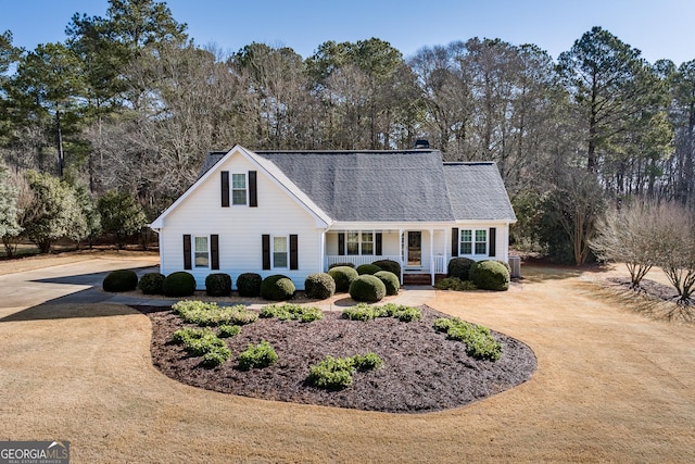 traditional-style house featuring a chimney, curved driveway, central AC, and roof with shingles