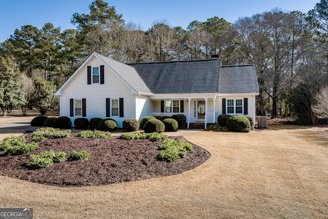 traditional home featuring driveway, a porch, cooling unit, a shingled roof, and a chimney