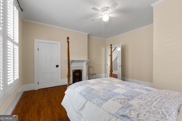 bedroom featuring multiple windows, wood finished floors, ornamental molding, and a fireplace