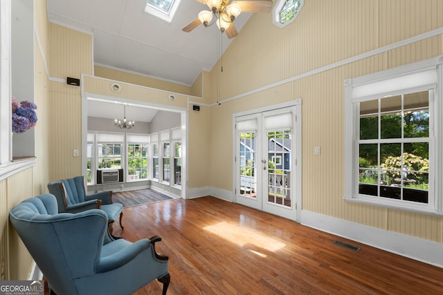 living area featuring hardwood / wood-style floors, a skylight, a healthy amount of sunlight, and visible vents