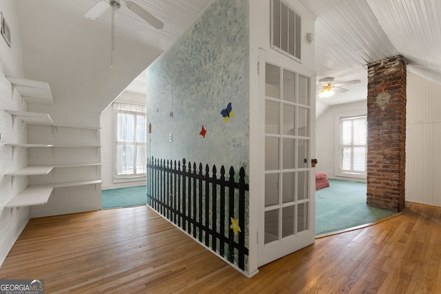 hallway featuring hardwood / wood-style floors, lofted ceiling, visible vents, and a wealth of natural light