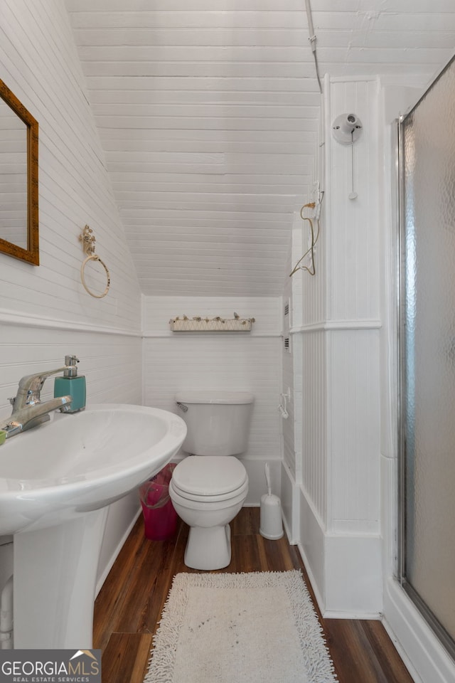 bathroom with lofted ceiling, toilet, wood finished floors, and a shower stall