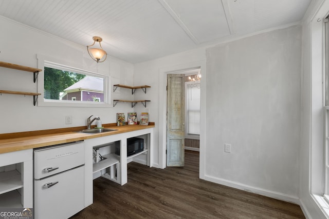 kitchen featuring open shelves, butcher block counters, dark wood-style flooring, white cabinets, and a sink