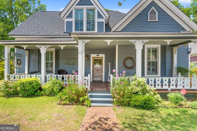 view of front of property featuring covered porch, a front yard, and roof with shingles