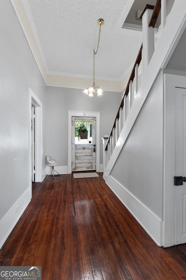 entrance foyer featuring hardwood / wood-style floors, stairway, baseboards, ornamental molding, and a notable chandelier