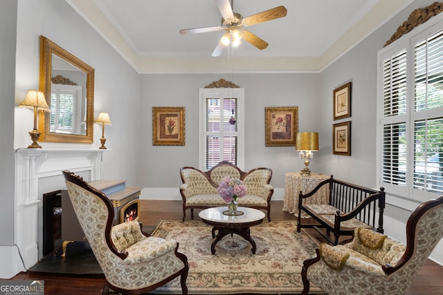 sitting room with a fireplace, crown molding, ceiling fan, and wood finished floors