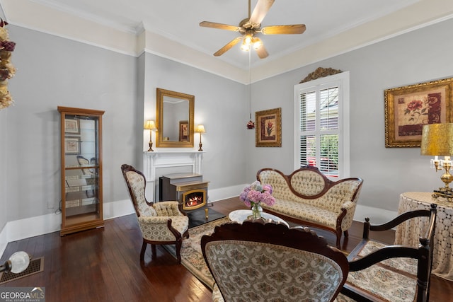 living area with dark wood finished floors, crown molding, baseboards, and ceiling fan