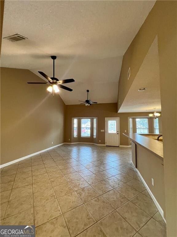 interior space with visible vents, baseboards, lofted ceiling, light tile patterned floors, and a textured ceiling