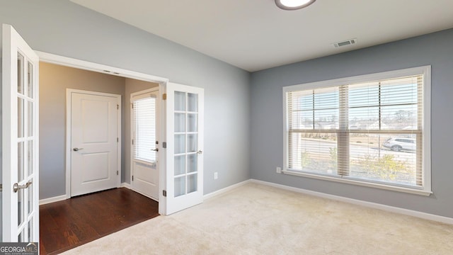 empty room featuring french doors, visible vents, carpet floors, and baseboards