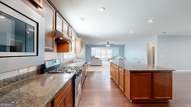 kitchen featuring visible vents, under cabinet range hood, a sink, open floor plan, and stainless steel appliances