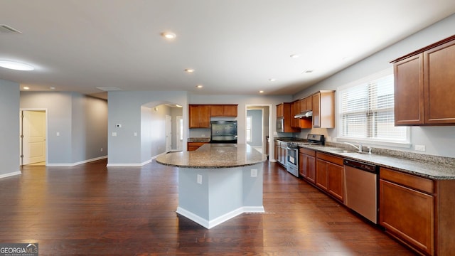 kitchen with dark wood-style floors, a kitchen island, stainless steel appliances, and a sink