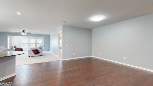 unfurnished living room with dark wood finished floors, visible vents, ceiling fan, and baseboards