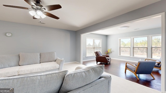 living room featuring visible vents, ceiling fan, baseboards, and wood finished floors