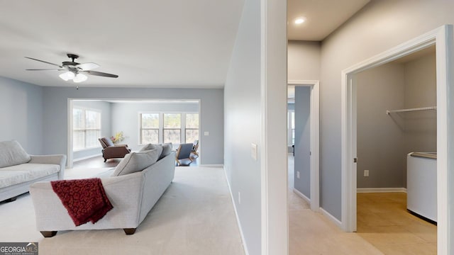 living room with light colored carpet, washer / clothes dryer, baseboards, and a ceiling fan