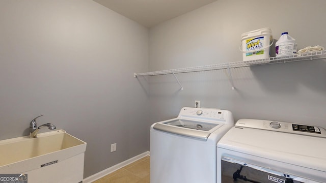 clothes washing area with a sink, washer and dryer, light tile patterned floors, baseboards, and laundry area