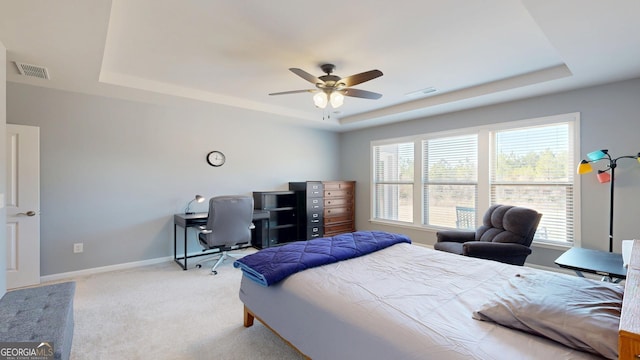 bedroom with visible vents, light colored carpet, baseboards, and a tray ceiling