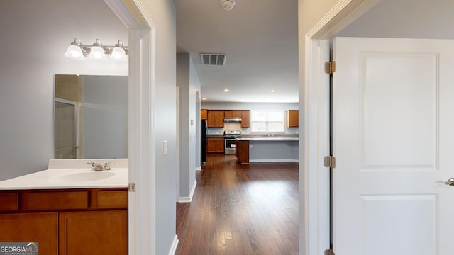 hall featuring visible vents, a sink, recessed lighting, baseboards, and dark wood-style flooring