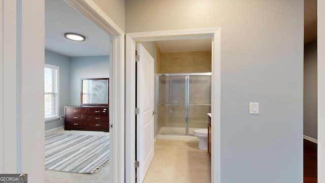 full bath with tile patterned floors, toilet, baseboards, and a stall shower