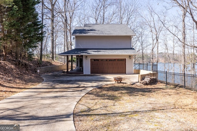 exterior space featuring a garage, roof with shingles, concrete driveway, and fence