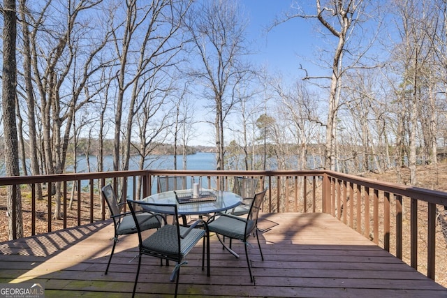 wooden terrace with a water view and outdoor dining space