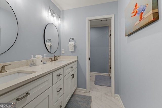 full bath with double vanity, baseboards, marble finish floor, and a sink