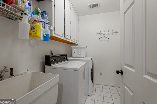 washroom featuring visible vents, washing machine and clothes dryer, light tile patterned flooring, cabinet space, and a sink