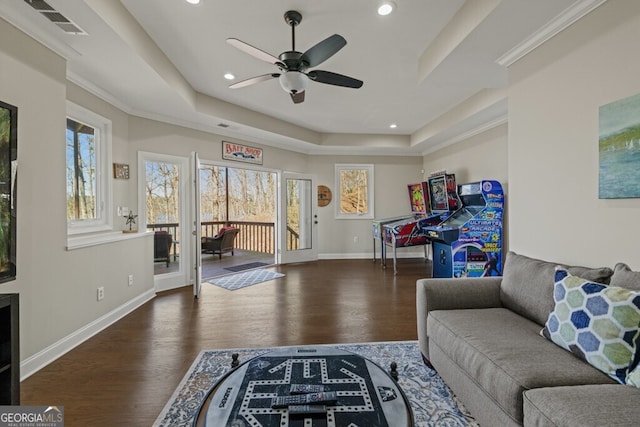 living area with ceiling fan, baseboards, a raised ceiling, and wood finished floors