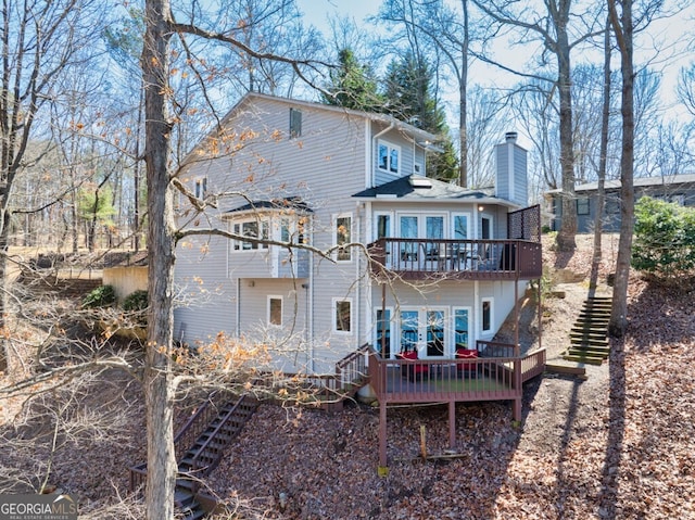 back of property with stairs, a deck, and a chimney