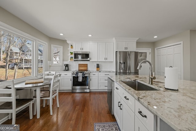 kitchen featuring tasteful backsplash, a sink, white cabinets, stainless steel appliances, and dark wood-style flooring