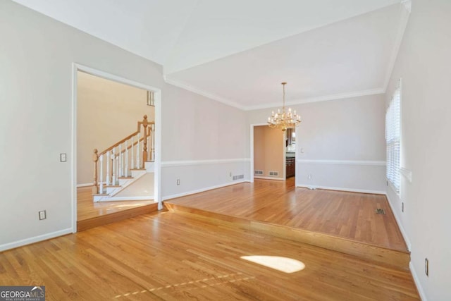 unfurnished room featuring a notable chandelier, wood finished floors, crown molding, baseboards, and stairs