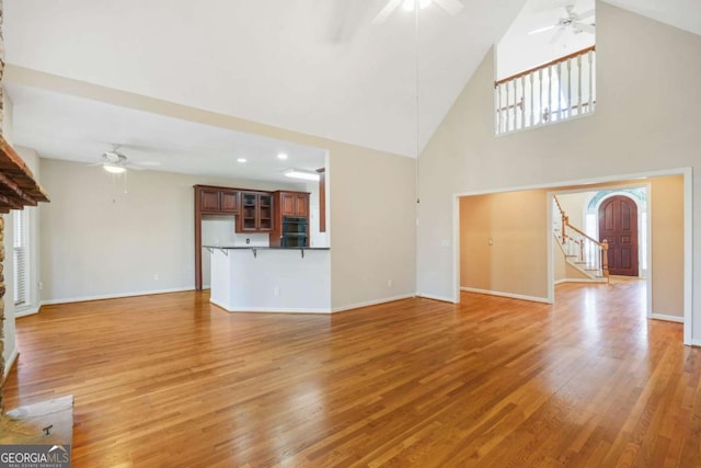 unfurnished living room featuring baseboards, light wood-style flooring, and a ceiling fan