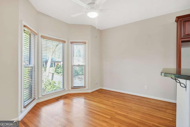 unfurnished room featuring light wood-style flooring, a ceiling fan, and baseboards