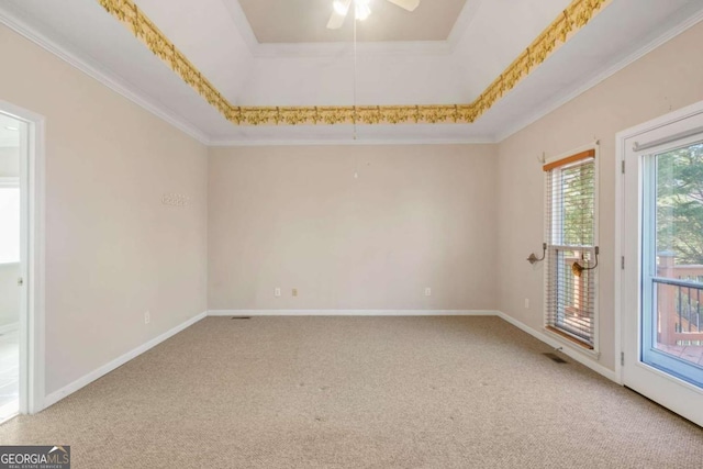 carpeted empty room featuring ceiling fan, baseboards, a tray ceiling, and ornamental molding