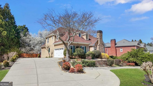 view of front of property featuring stucco siding, concrete driveway, an attached garage, and fence