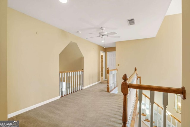 hall featuring carpet, an upstairs landing, visible vents, and baseboards