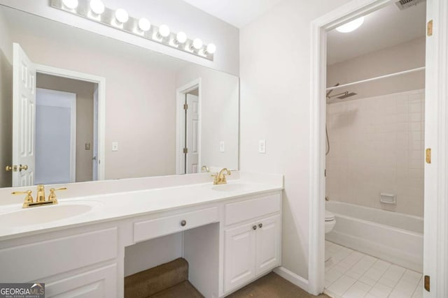 bathroom featuring double vanity, tile patterned flooring, toilet, and a sink