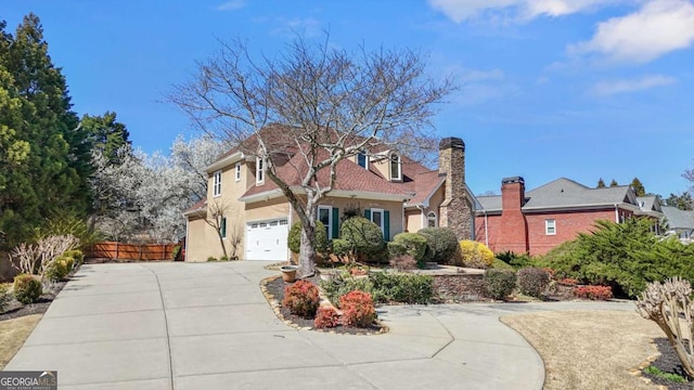 view of front of house with stucco siding, concrete driveway, a garage, and fence