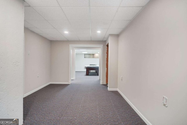 hallway with recessed lighting, a drop ceiling, dark carpet, and baseboards